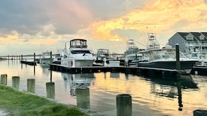 A marina with several boats docked, wooden pilings, and a grassy area in the foreground. - Waterfront Bethany Beach Cottage, Walk to Beach, Fish, Kayak - Dewey Rehoboth (Bethany Beach)