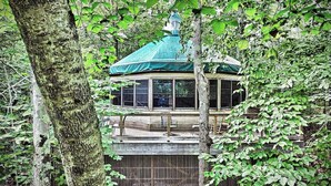 A gazebo with a green roof, surrounded by trees and a wooden deck. - Island Tree House Glamping (Monmouth)