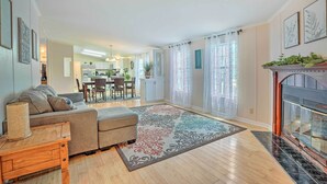 A living room with a sofa, ottoman, and a fireplace. There is a dining area in the background with a table and chairs. - Mt Pleasant Retreat w/ Grill: 10 Mi to Beach (Mt Pleasant)