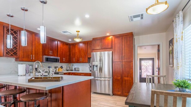 A modern kitchen with wooden cabinets, stainless steel appliances, and a bar area with stools. - Downtown Tempe House Beauty with yard! Mill 3 blocks. ASU half mile.  (Tempe)