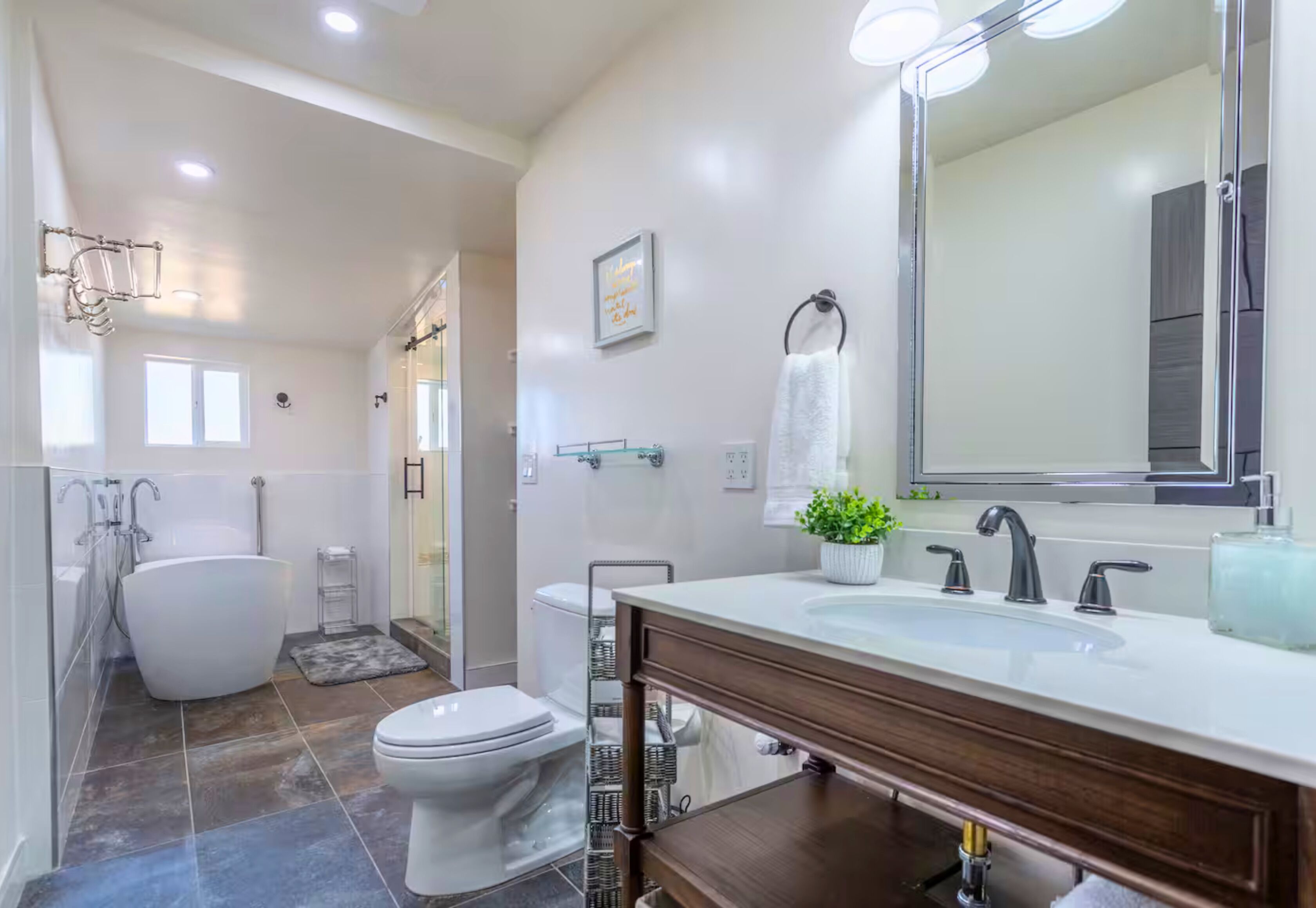 A modern bathroom with a freestanding bathtub, a large mirror, and a vanity with a sink.