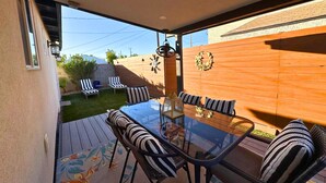 A glass-top dining table with striped cushions, a wooden fence, and a small garden area with a lawn and chairs. - Downtown Tempe House Beauty with yard! Mill 3 blocks. ASU half mile.  (Tempe)