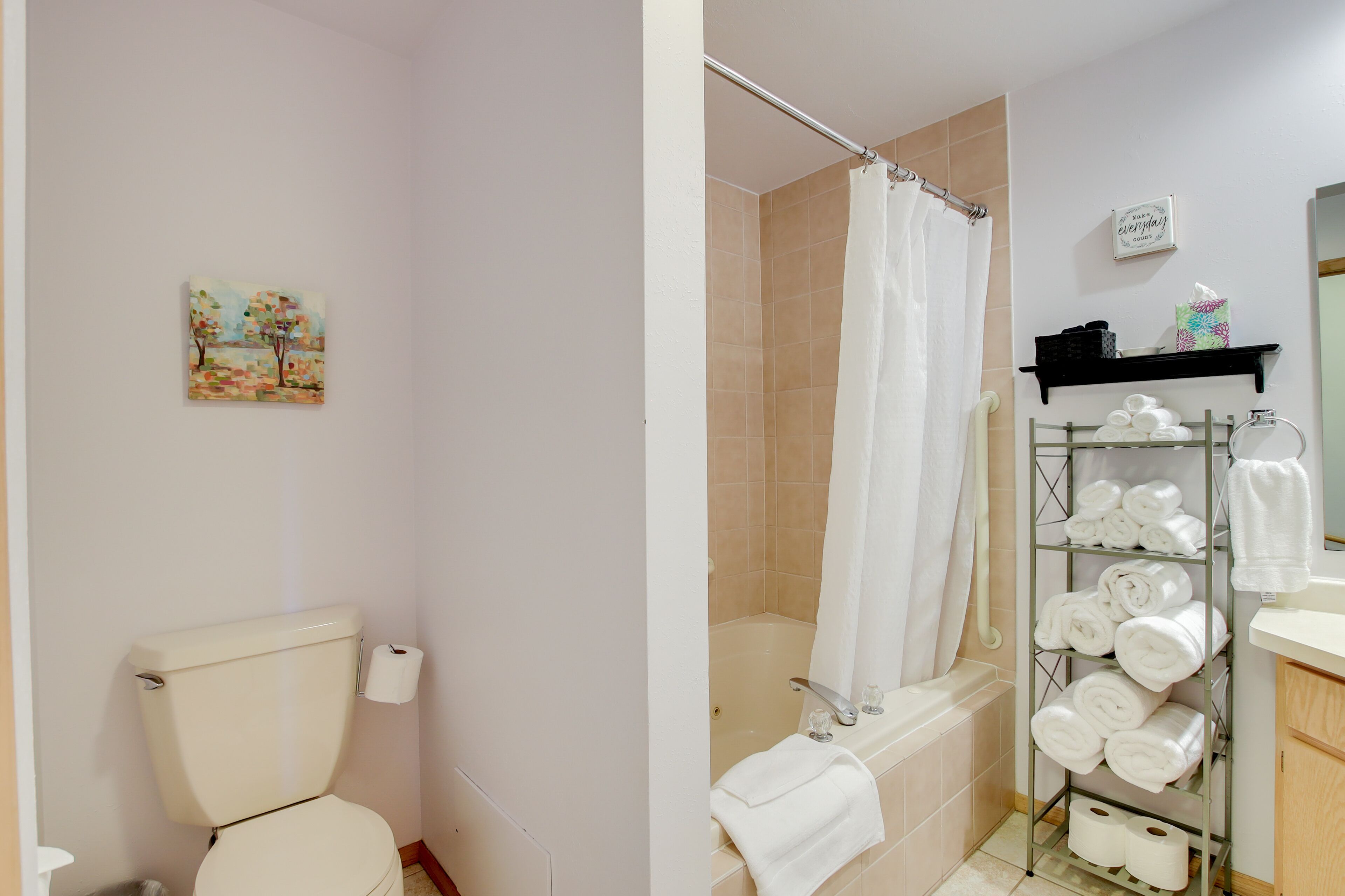 A bathroom with a toilet, shower, and a shelf with towels and toiletries.