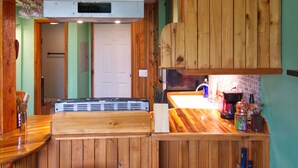 A kitchen with wooden cabinets, a countertop, a sink, and a bar stool.