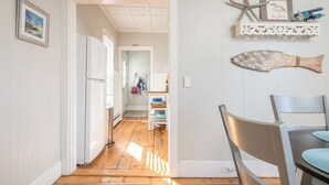 Un pasillo con piso de madera que conduce a una zona de cocina con una mesa y sillas.