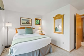 A bedroom with a bed, bedside lamp, wall-mounted mirror, and framed pictures. - Prime Fish Creek Location: Holiday by the Bay (Fish Creek)