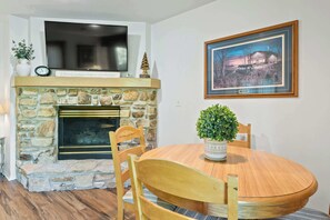 A dining area with a stone fireplace, a television mounted above it, and a framed picture on the wall. - Prime Fish Creek Location: Holiday by the Bay (Fish Creek)