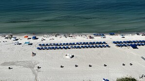 A beach with rows of blue umbrellas and white tents, a sandy shore, and the ocean in the background. - SUNRISE /SUNSET GULF VIEWS #932 - FREE BEACH CHAIRS!!!!! (Panama City)