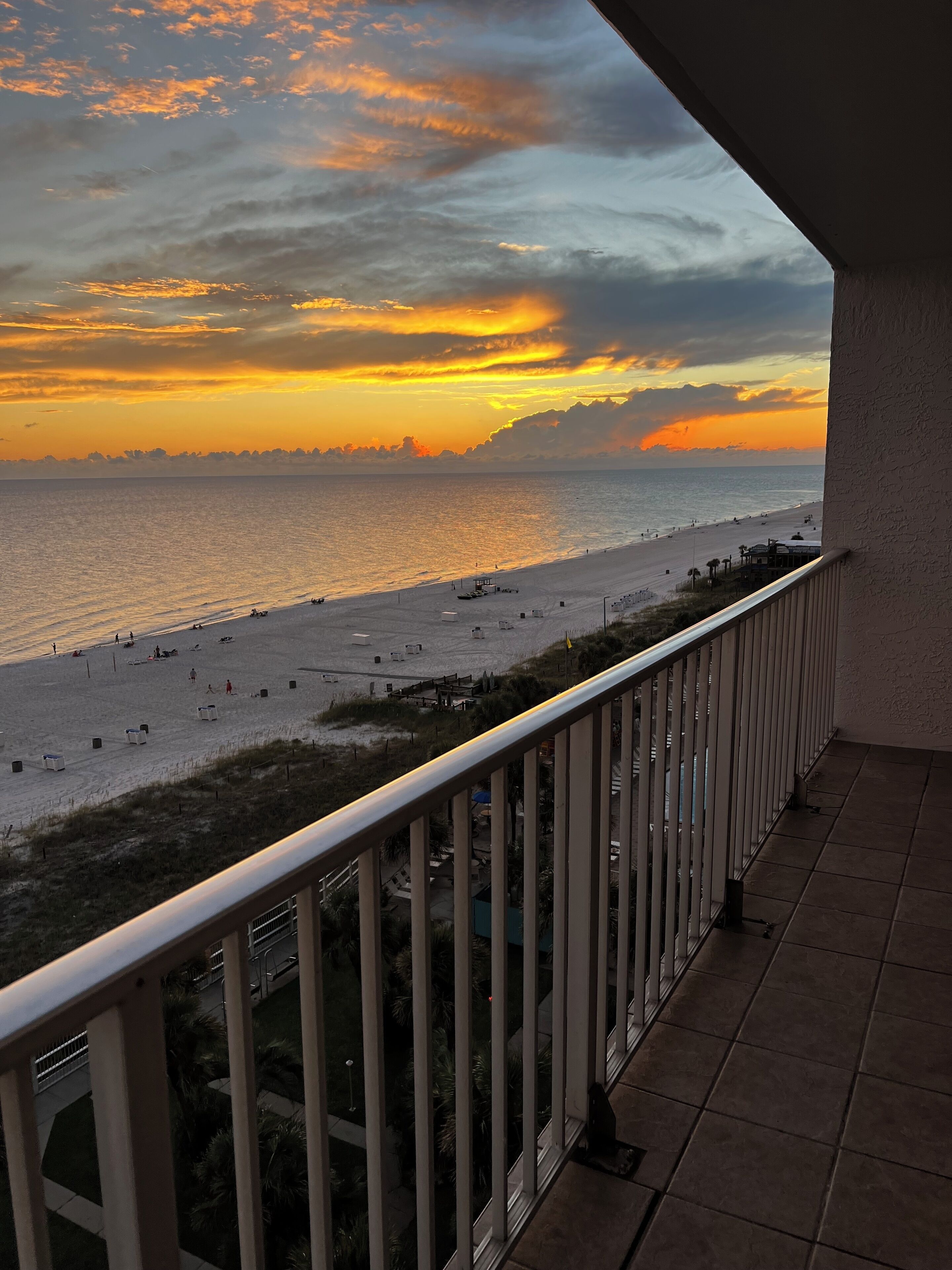 Ein Balkon mit Blick auf einen Strand bei Sonnenuntergang.