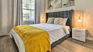 A modern bedroom with a large bed, a nightstand with a lamp, and abstract wall art. - Vista Cay Resort Condo ~ 5 Mi to Universal! (Orlando)