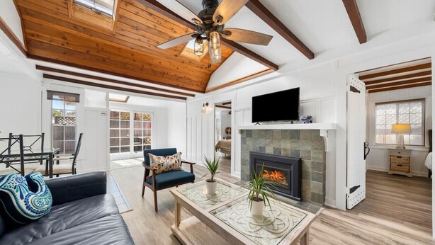 A spacious living room with a fireplace, a ceiling fan, and a television. - Charming Hillcrest/Mission Hills 3 BR + House (San Diego)