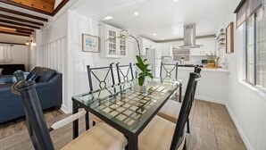 A modern kitchen with white cabinets, a glass dining table, and a black chair. - Charming Hillcrest/Mission Hills 3 BR + House (San Diego)
