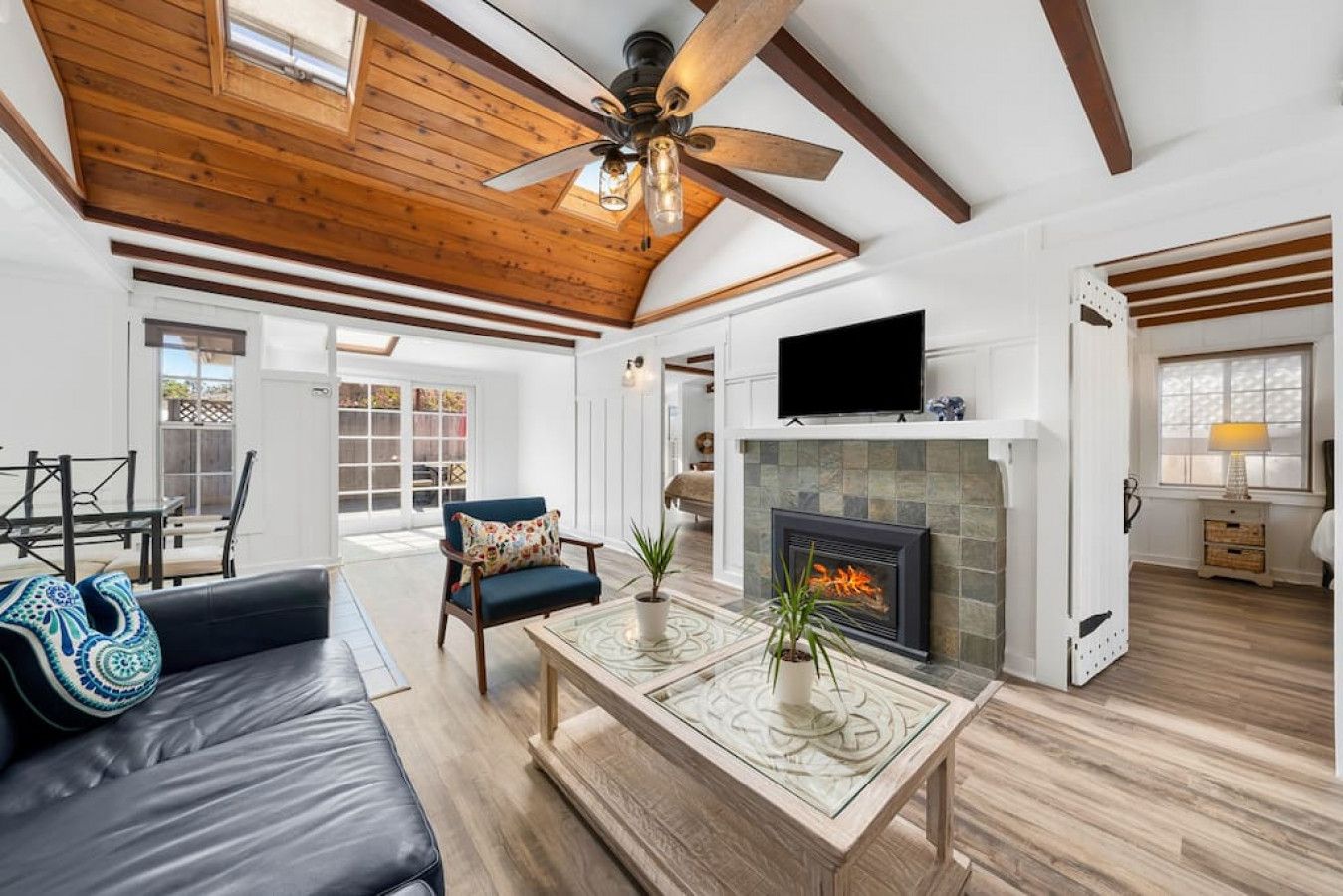 A spacious living room with a fireplace, a ceiling fan, and a television.