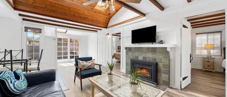 A spacious living room with a fireplace, a ceiling fan, and a television.