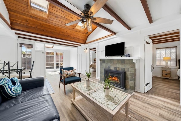 Una sala de estar amplia con chimenea, ventilador de techo y televisor.