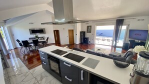 A modern kitchen with a central island, dining area, and a living space with a view.