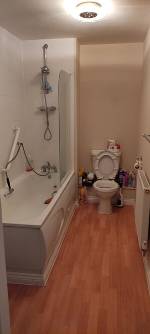 Een badkamer met een bad, toilet en douche.