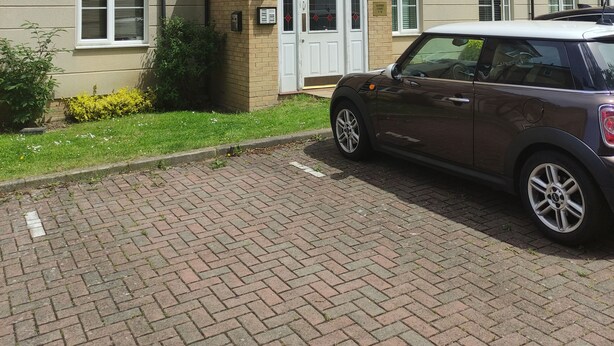 A multi-story residential building with a brick facade, a small front porch, and a parked car. - Immaculate 1-Bed Apartment in Borehamwood (Borehamwood)