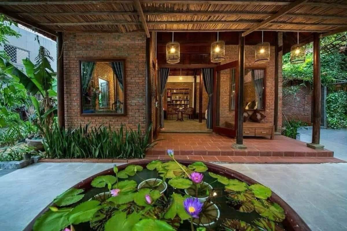 A traditional-style building with a brick exterior, a covered entrance, and a pond with water lilies.