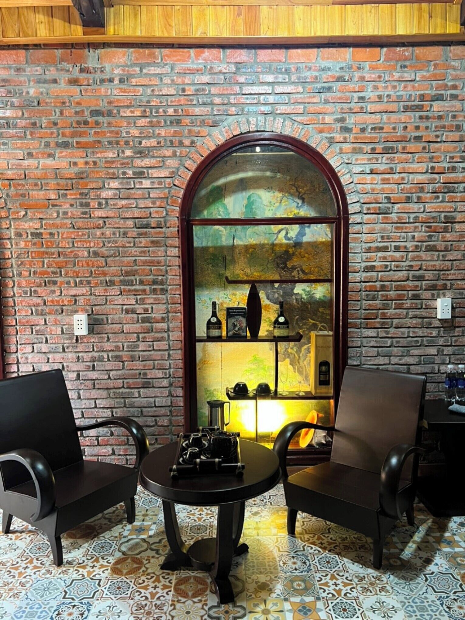 A cozy seating area with a brick wall, a round table, and two chairs.