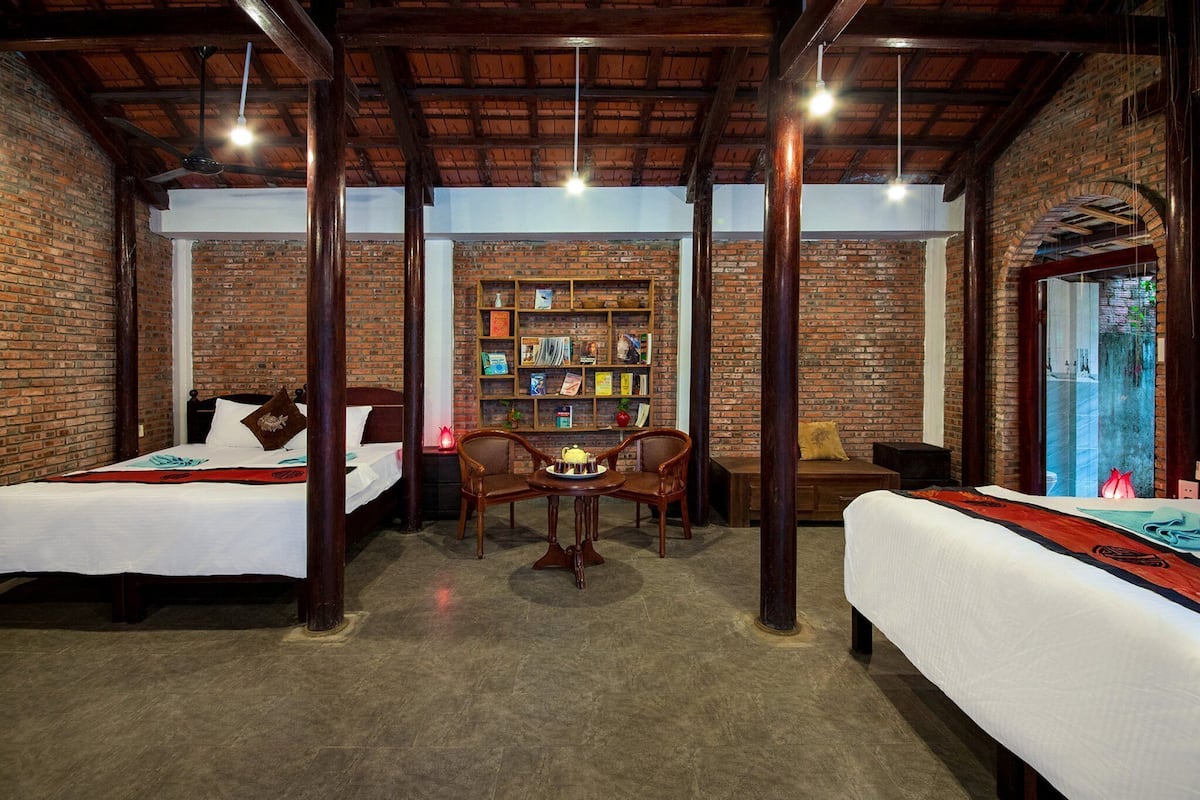 A room with two beds, a wooden table, and a bookshelf.