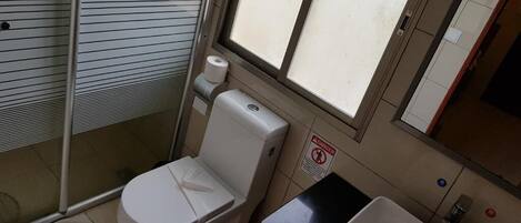 Une petite salle de bain avec des toilettes, un lavabo et une fenêtre.