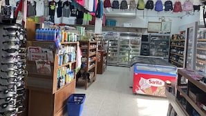 A store with shelves of sunglasses, a refrigerator, and various clothing items. - Caye Caulker Beach Hotel (Caye Caulker)