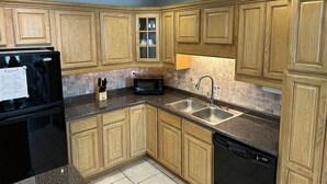 A kitchen with wooden cabinets, a black refrigerator, a microwave, a sink, and a dishwasher.