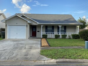 A single-story house with a garage, a front porch with a railing, and a small front yard.