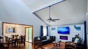 A spacious living area with a dining table, a sofa, and a TV mounted on the wall.
