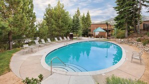 A circular pool with lounge chairs and a small building in the background.