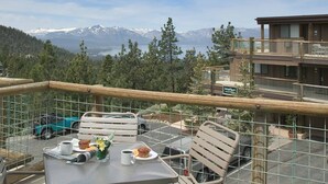 A balcony with a table set for breakfast, overlooking a mountainous landscape.