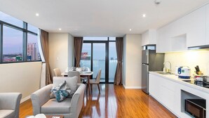 Una habitación de hotel moderna con comedor, sofá, mesa de centro y cocina equipada con refrigerador y microondas.