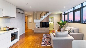 Una sala de estar moderna con chimenea empotrada, televisor de pantalla plana y una escalera que lleva a un nivel superior.