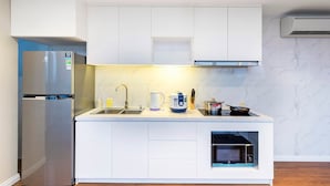 Una cocina moderna con armarios blancos, un refrigerador de acero inoxidable, un horno empotrado y un microondas.