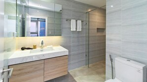 Un baño moderno con cabina de ducha de vidrio, un lavabo blanco y un espejo grande.