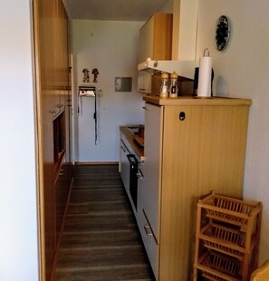 Kompakti keittiö, jossa on puukalusteet, sisäänrakennettu uuni ja mikroaaltouuni.