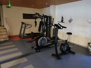 Kuntosali, jossa on kuntopyörät ja muut kardiolaitteet, painonnostovälineet sekä portaikko.