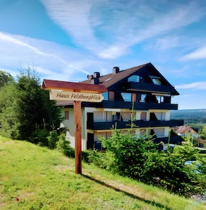 Une maison à deux étages, avec une enseigne indiquant « Haus Feldbergblick » devant l’entrée.