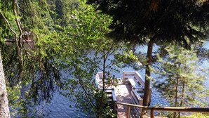 A wooden deck leading to a dock over water, surrounded by trees.