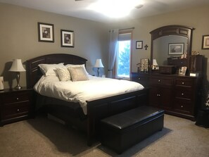 Cozy retreat with a large bed, dresser, and two bedside tables, each with a lamp.