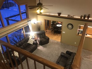 Relax in this stylish living area with a high ceiling and expansive outdoor views, featuring a comfortable seating area and dining space.