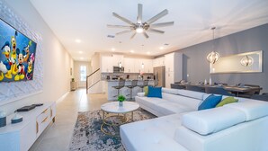 A modern living room with a white sofa, a coffee table, and a ceiling fan.