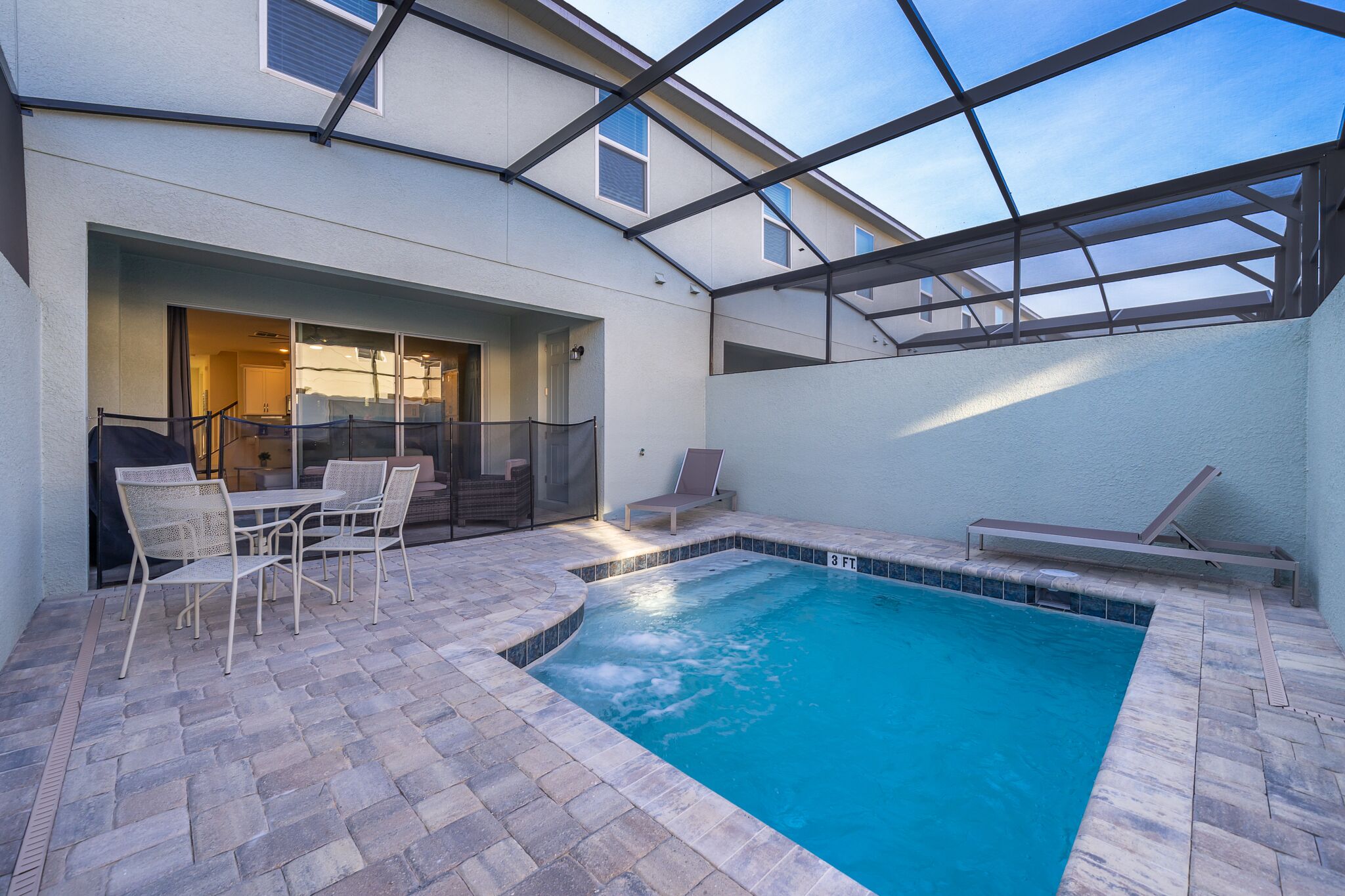Una piscina con techo de vidrio, mobiliario exterior y una zona de patio.