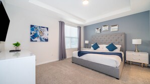 A bedroom with a bed, bedside tables, a TV, and a painting on the wall.