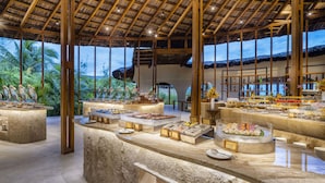 A buffet area with a tropical view, wooden beams, and a thatched roof. - Ana Mandara Cam Ranh (Cam Lam)