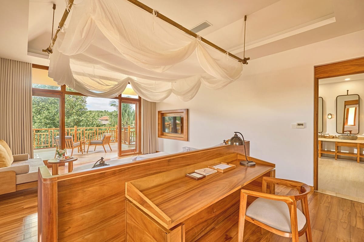 A wooden bar area with a large window, a hanging canopy, and a view of the outdoors.
