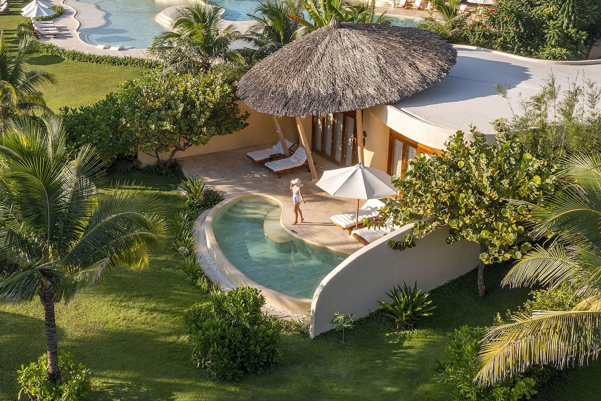 A resort with a pool, lounge chairs, and a thatched-roof structure.