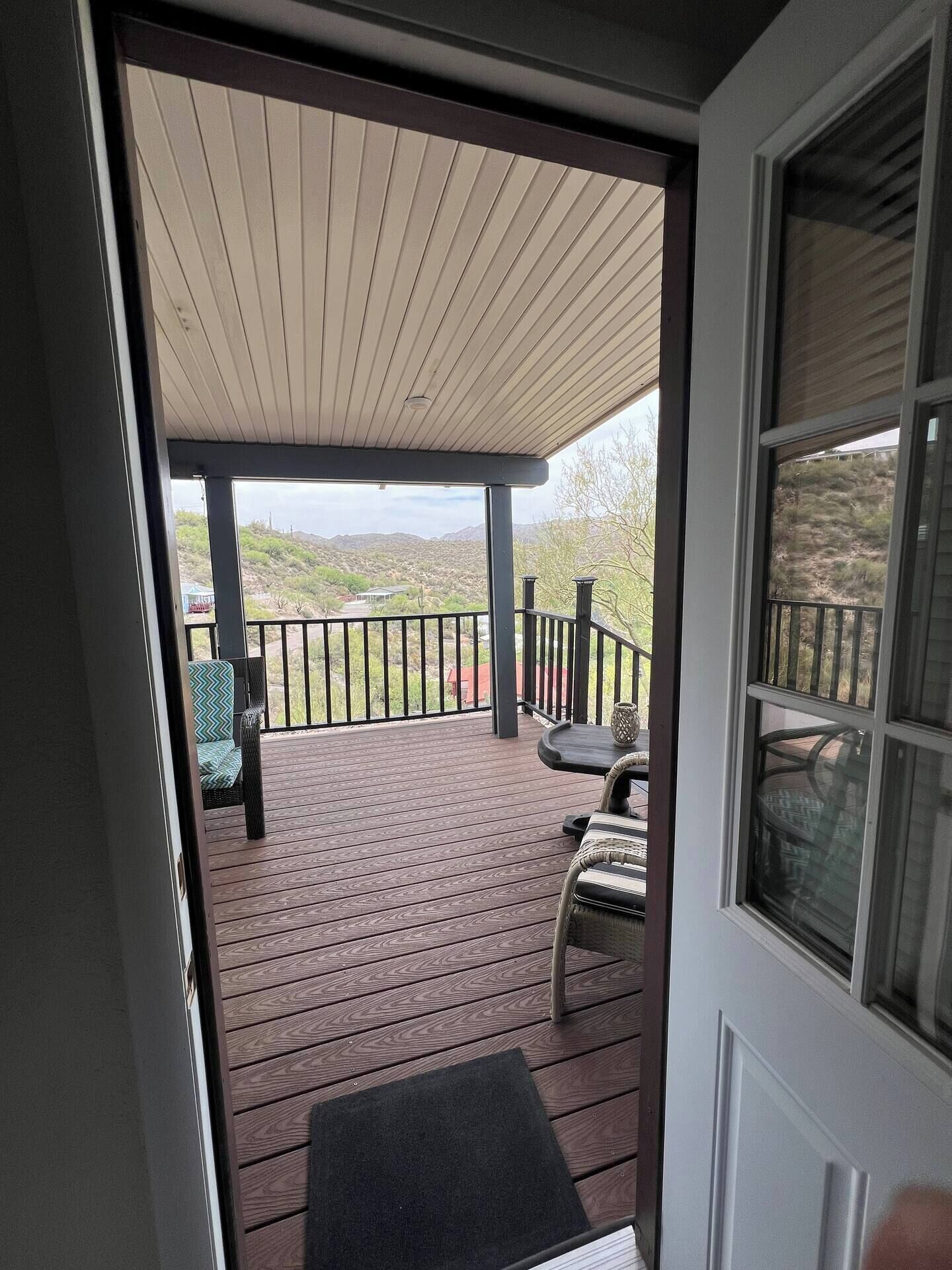 A wooden deck with outdoor furniture, a covered area, and a view of a hilly landscape.