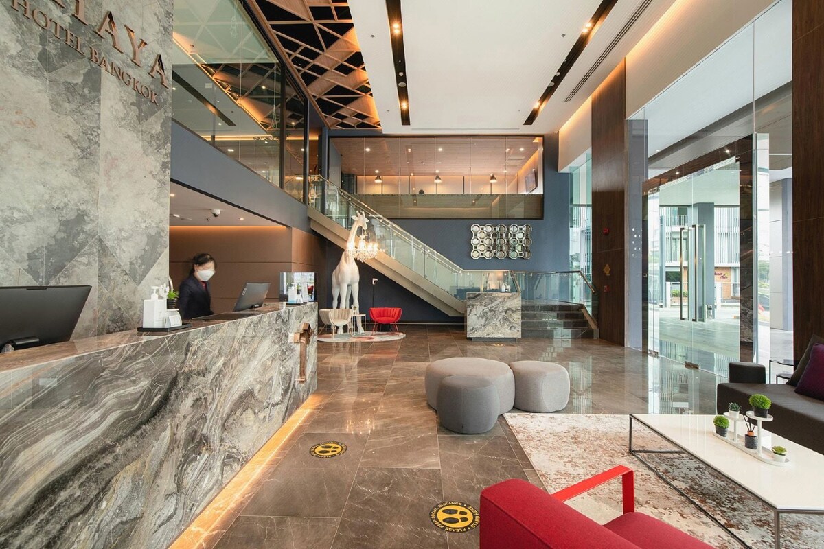 Hall d'albergo con reception, una scala e un'ampia parete in vetro.
